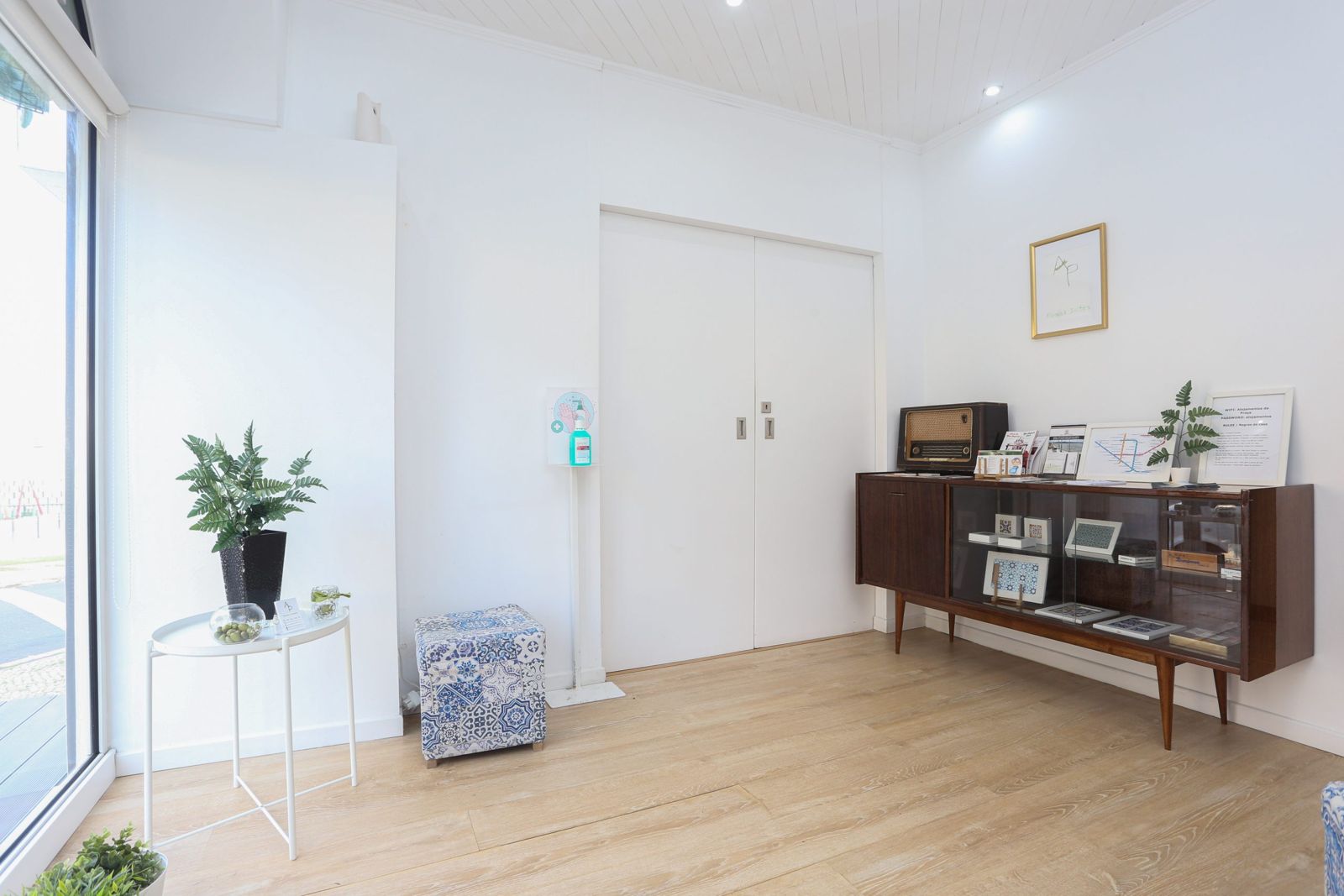 Receção com móvel vintage, rádio antigo, azulejos e pufe com padrão de azulejo